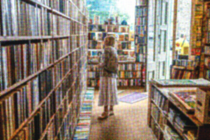 Older woman standing in front of a tall book shelf, wanting to have access to books, empty handed.
